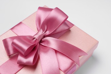 Photo of Gift box with pink bow on light grey background, closeup