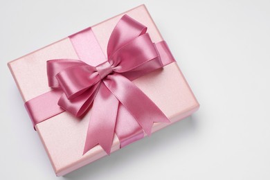 Photo of Gift box with pink bow on light grey background, top view