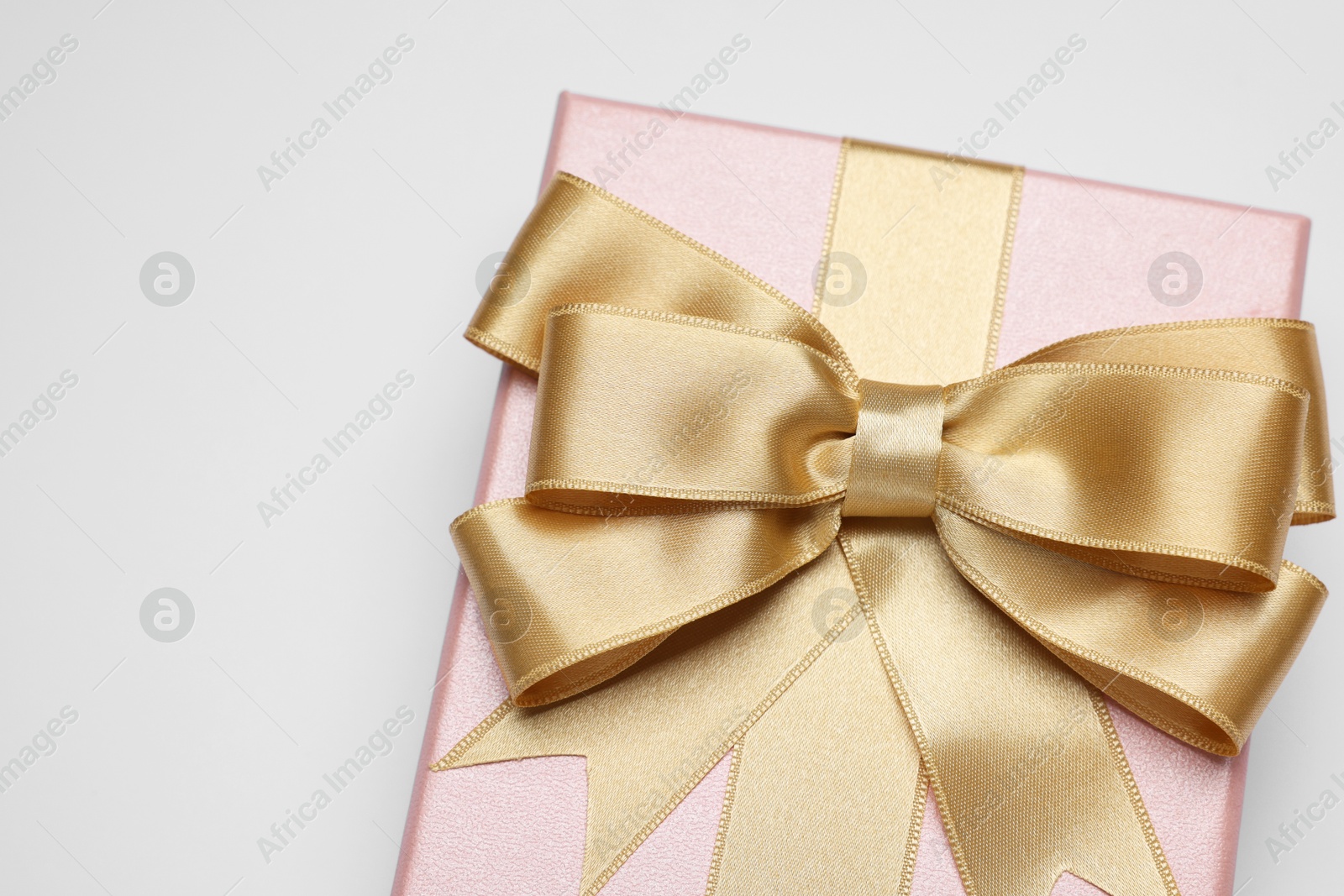 Photo of Gift box with golden bow on light grey background, above view