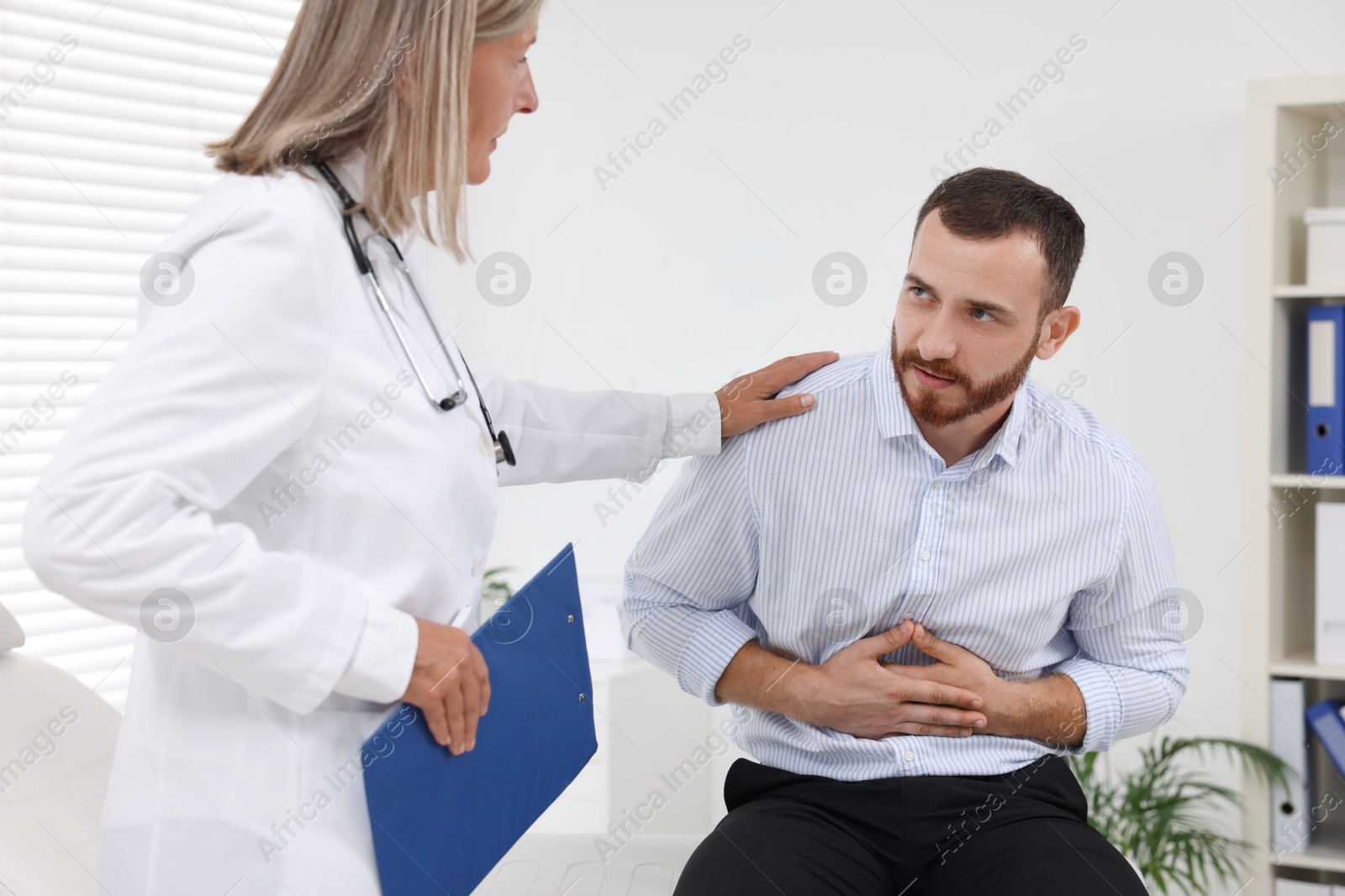 Photo of Doctor consulting patient with stomach pain in clinic