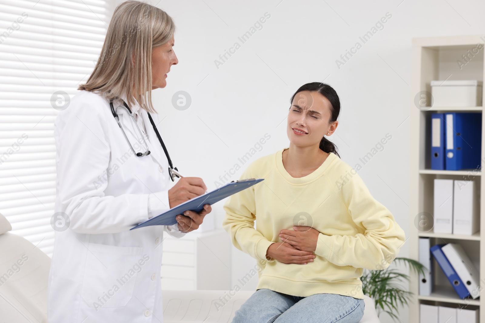 Photo of Senior doctor consulting patient with stomach pain in hospital