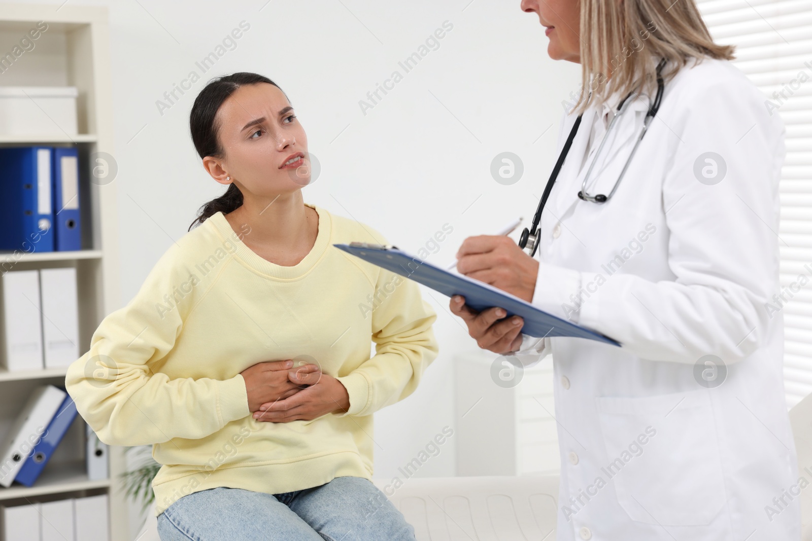 Photo of Doctor consulting patient with stomach pain in clinic, closeup