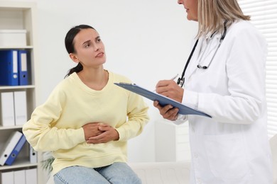 Doctor consulting patient with stomach pain in clinic, closeup