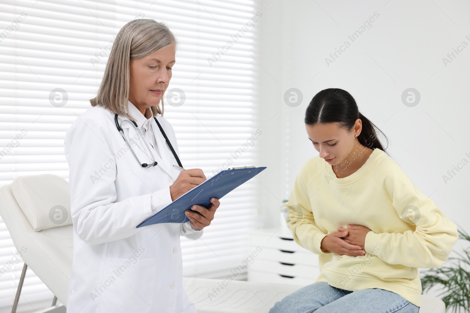 Photo of Senior doctor consulting patient with stomach pain in hospital