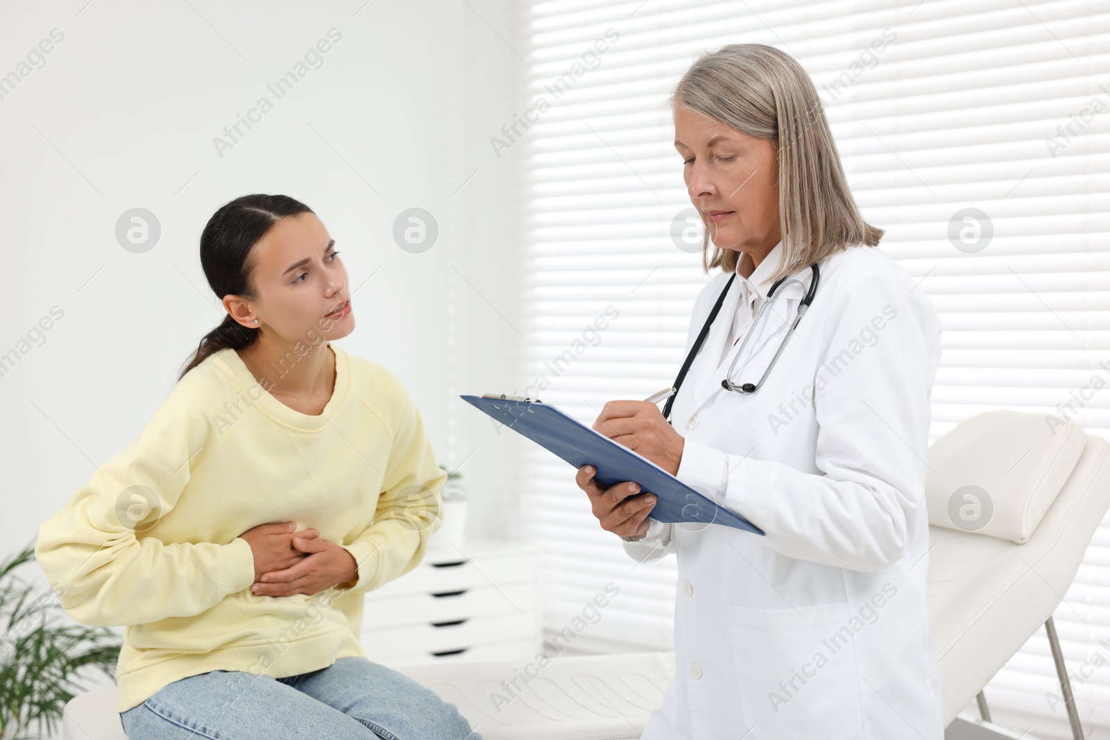 Photo of Senior doctor consulting patient with stomach pain in hospital