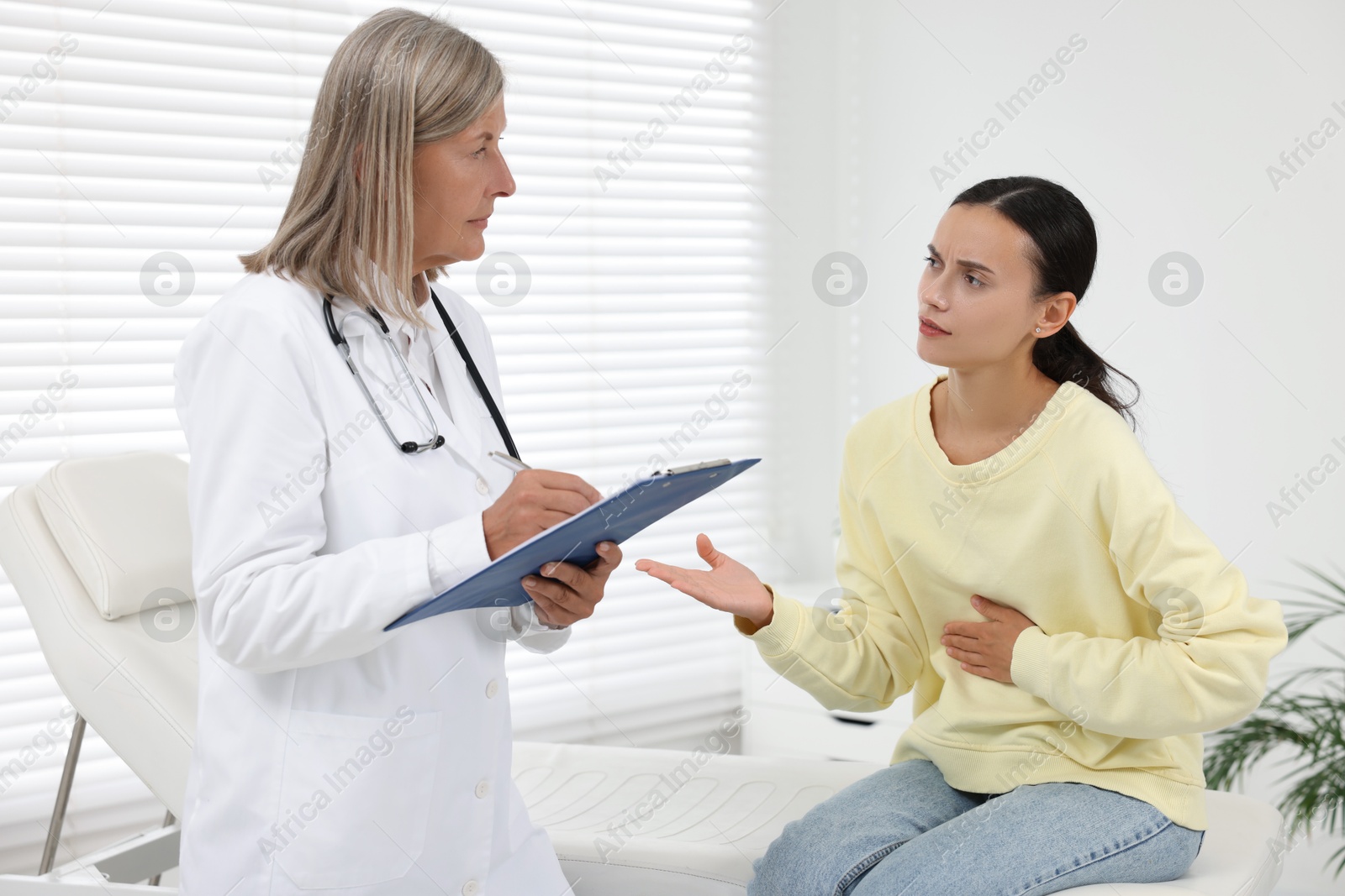 Photo of Senior doctor consulting patient with stomach pain in hospital