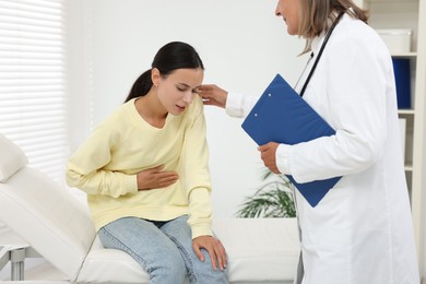 Doctor consulting patient with stomach pain in hospital, closeup