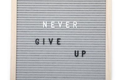 Photo of Letter board with phrase Never give up on white background, top view