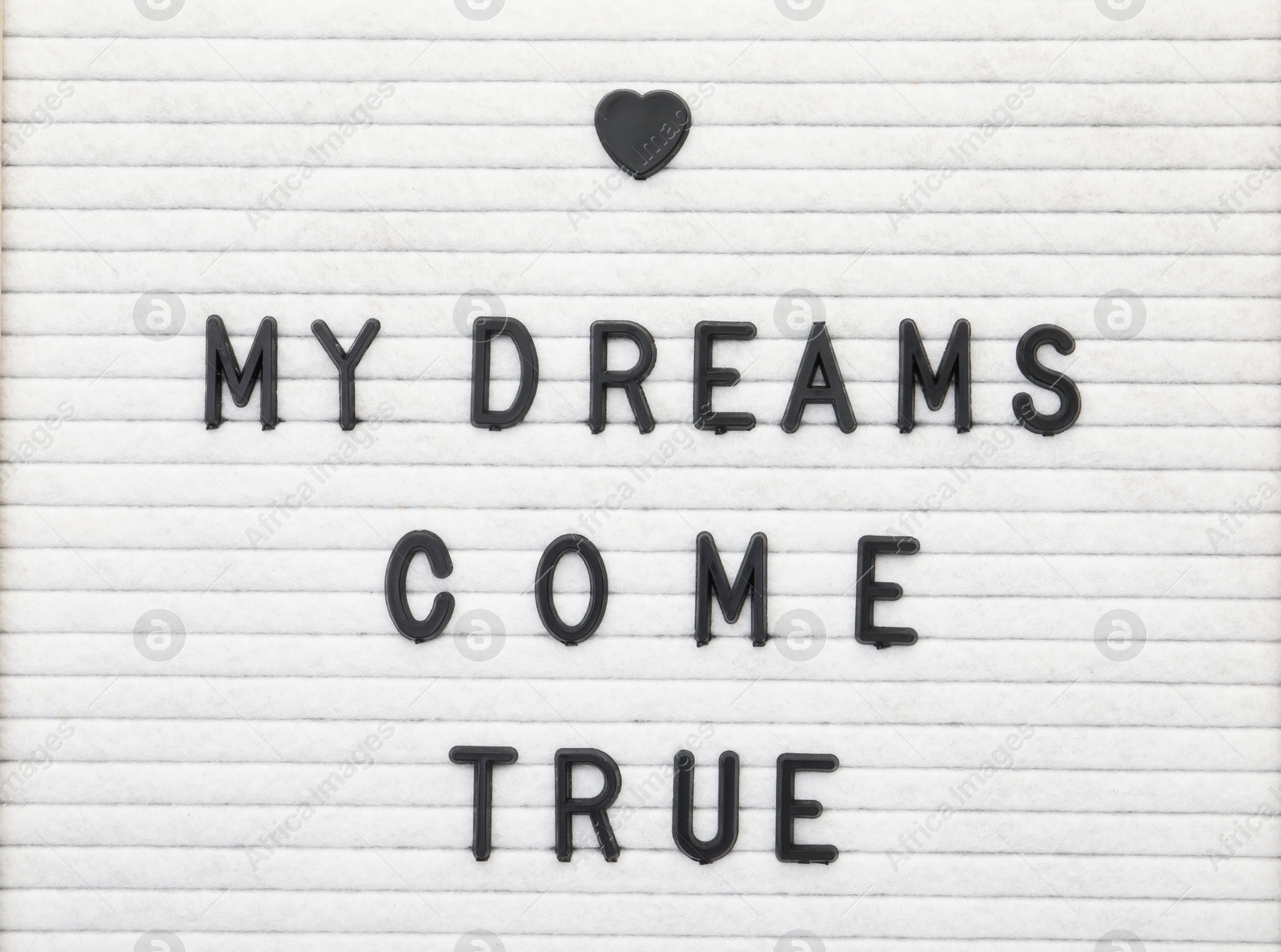 Photo of Letter board with phrase My dreams come true as background, top view