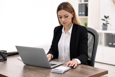 Photo of Banker with laptop and calculator working at wooden table in office