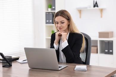 Photo of Banker with laptop working at wooden table in office