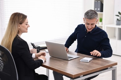 Photo of Banker working with client at wooden table in office