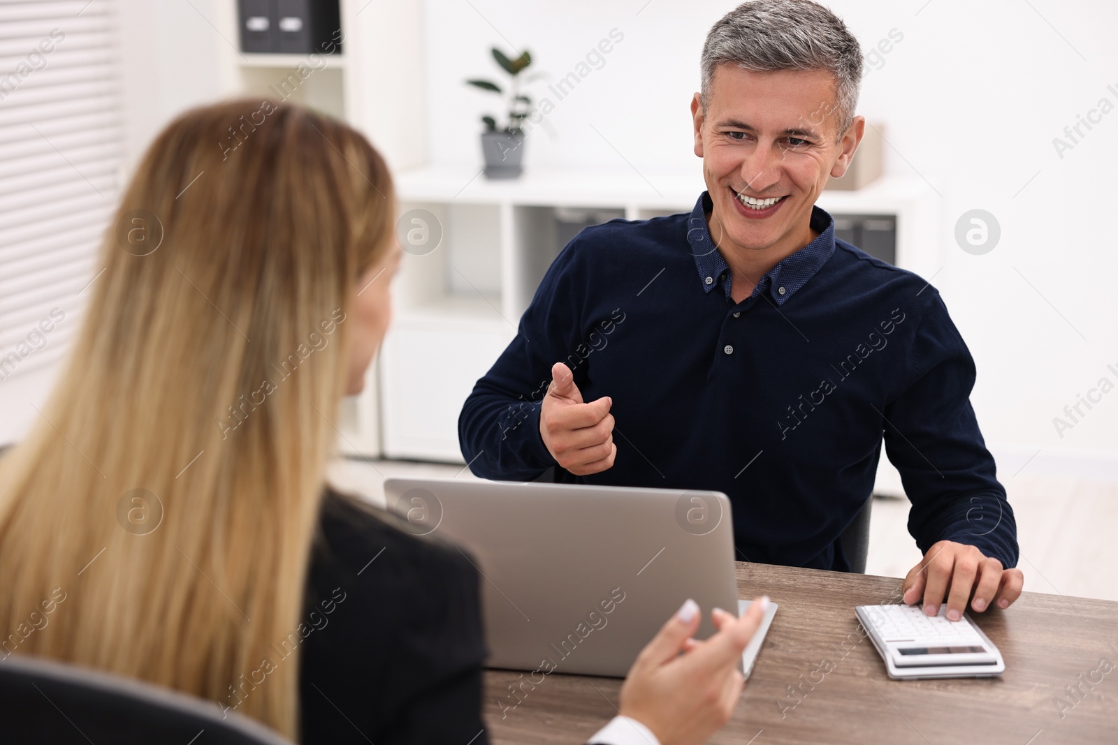 Photo of Banker working with client at wooden table in office