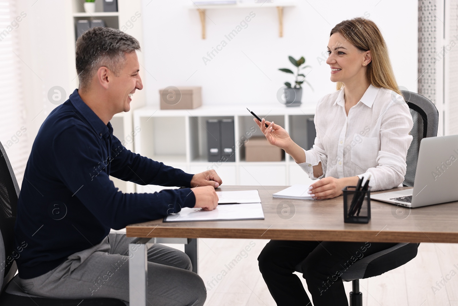 Photo of Banker working with client at wooden table in office