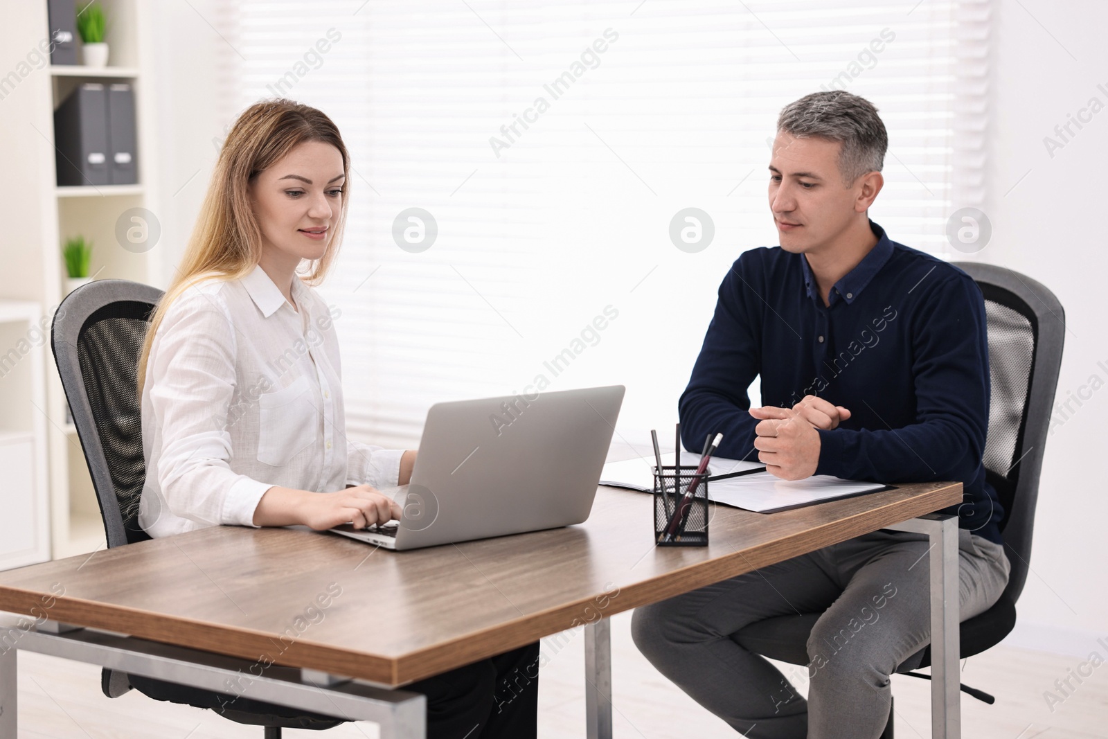 Photo of Banker working with client at wooden table in office