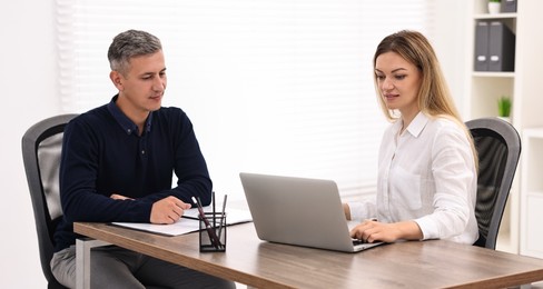 Banker working with client at wooden table in office