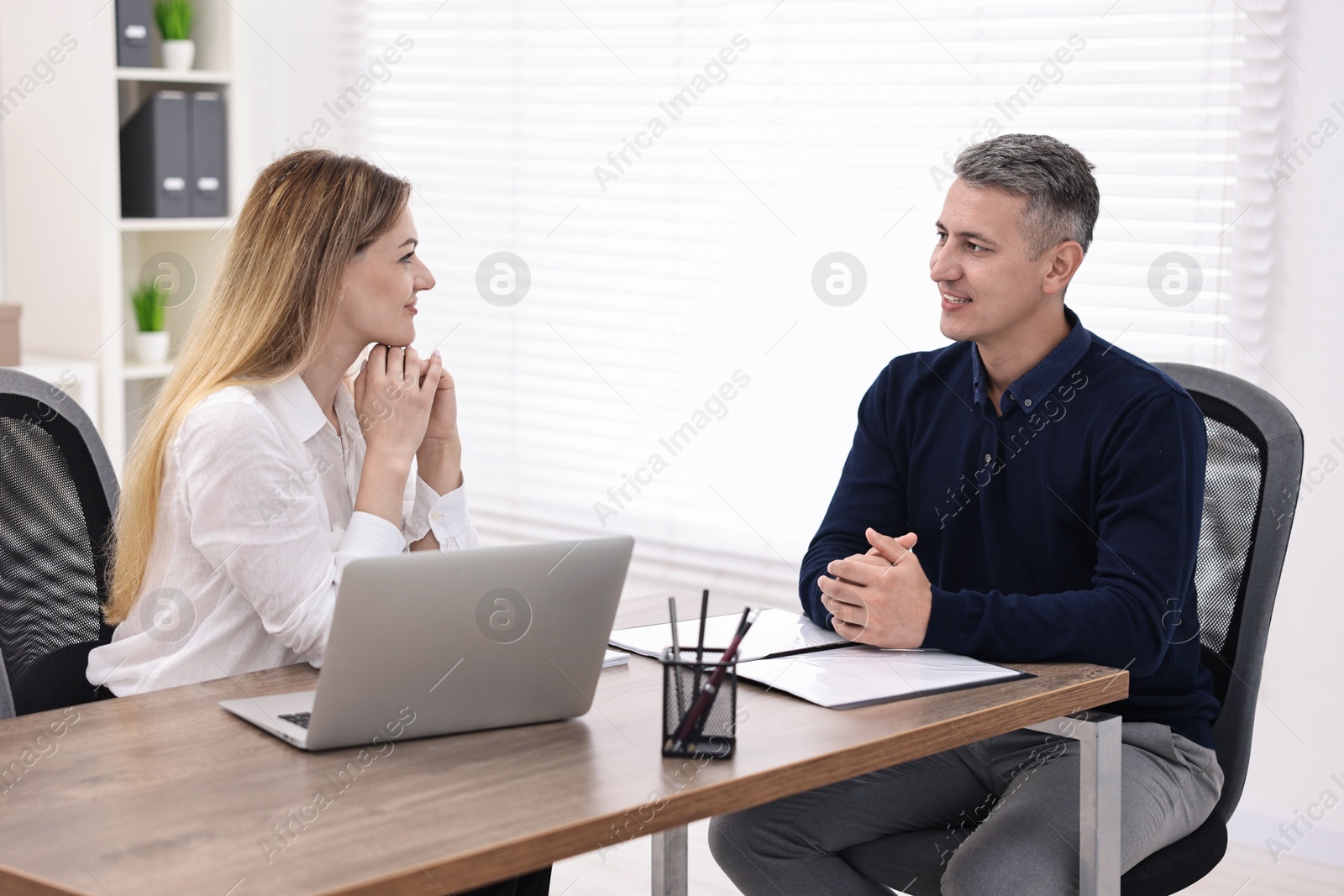 Photo of Banker working with client at wooden table in office