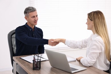 Banker and client shaking hands at table in office