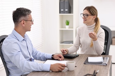 Photo of Banker working with client at table in office