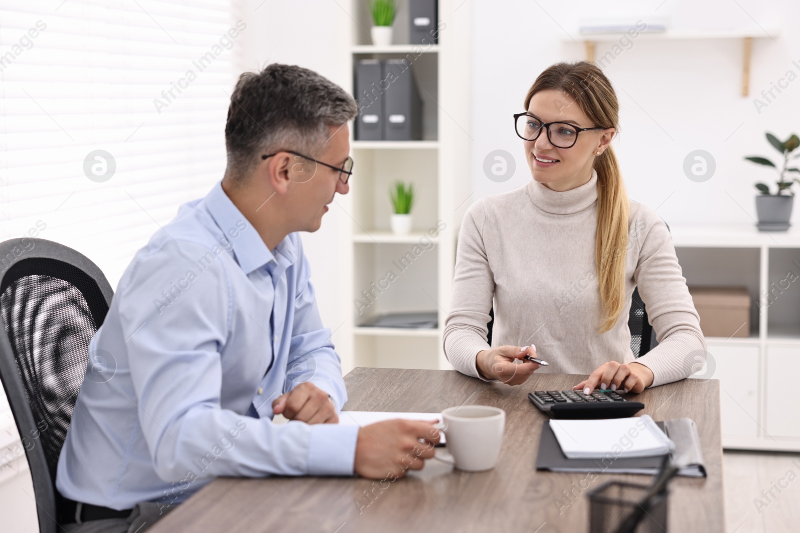 Photo of Banker working with client at table in office