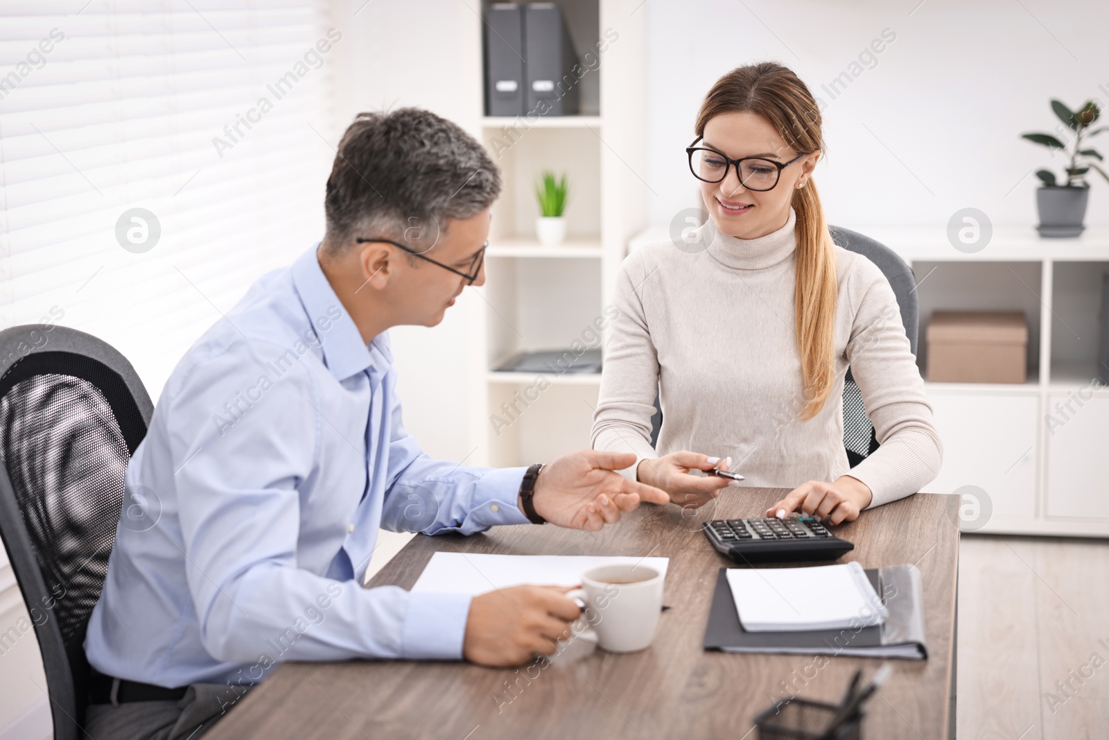 Photo of Banker working with client at table in office