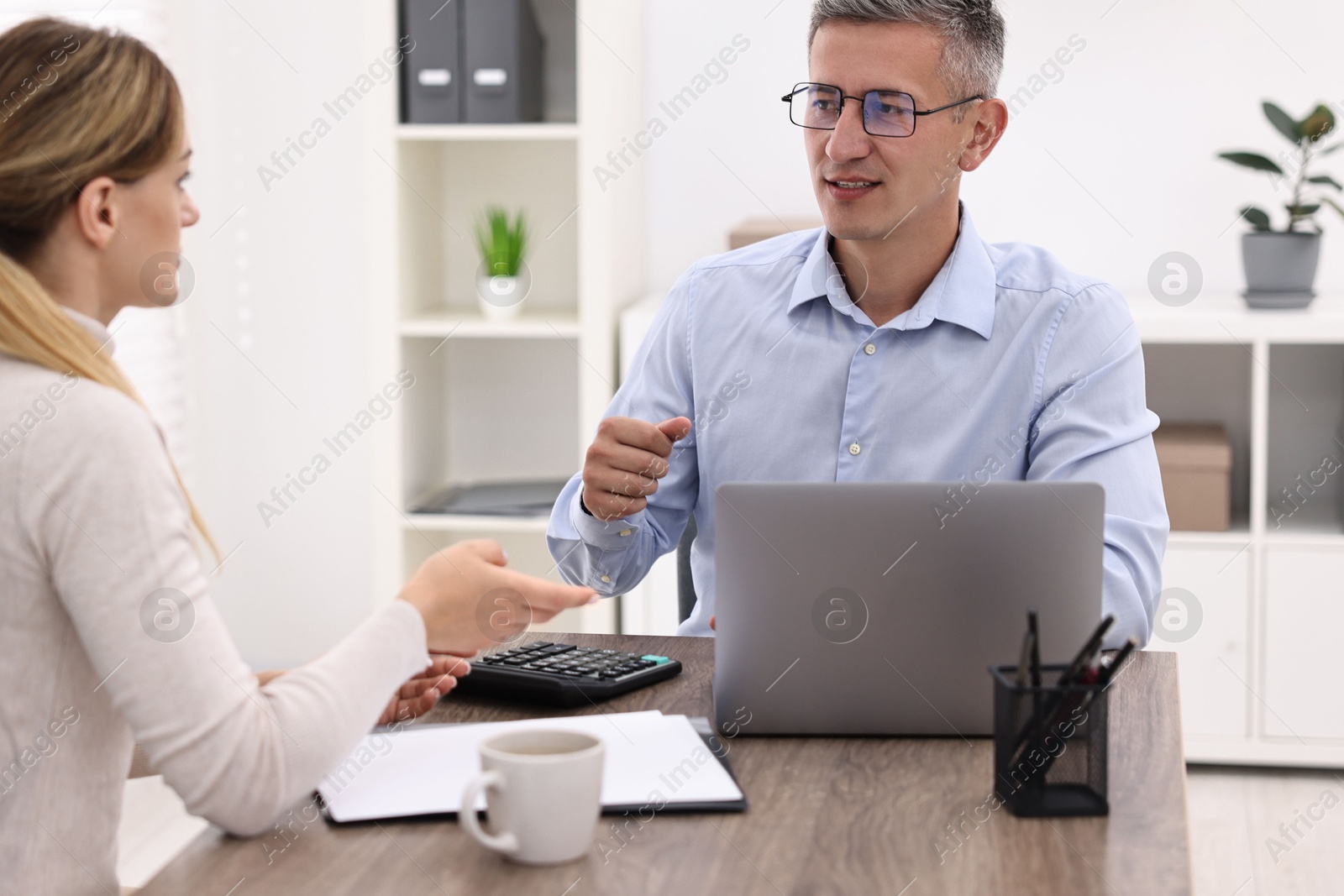 Photo of Banker working with client at table in office