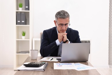 Banker with laptop working at wooden table in office