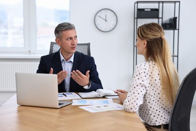 Banker working with client at wooden table in office