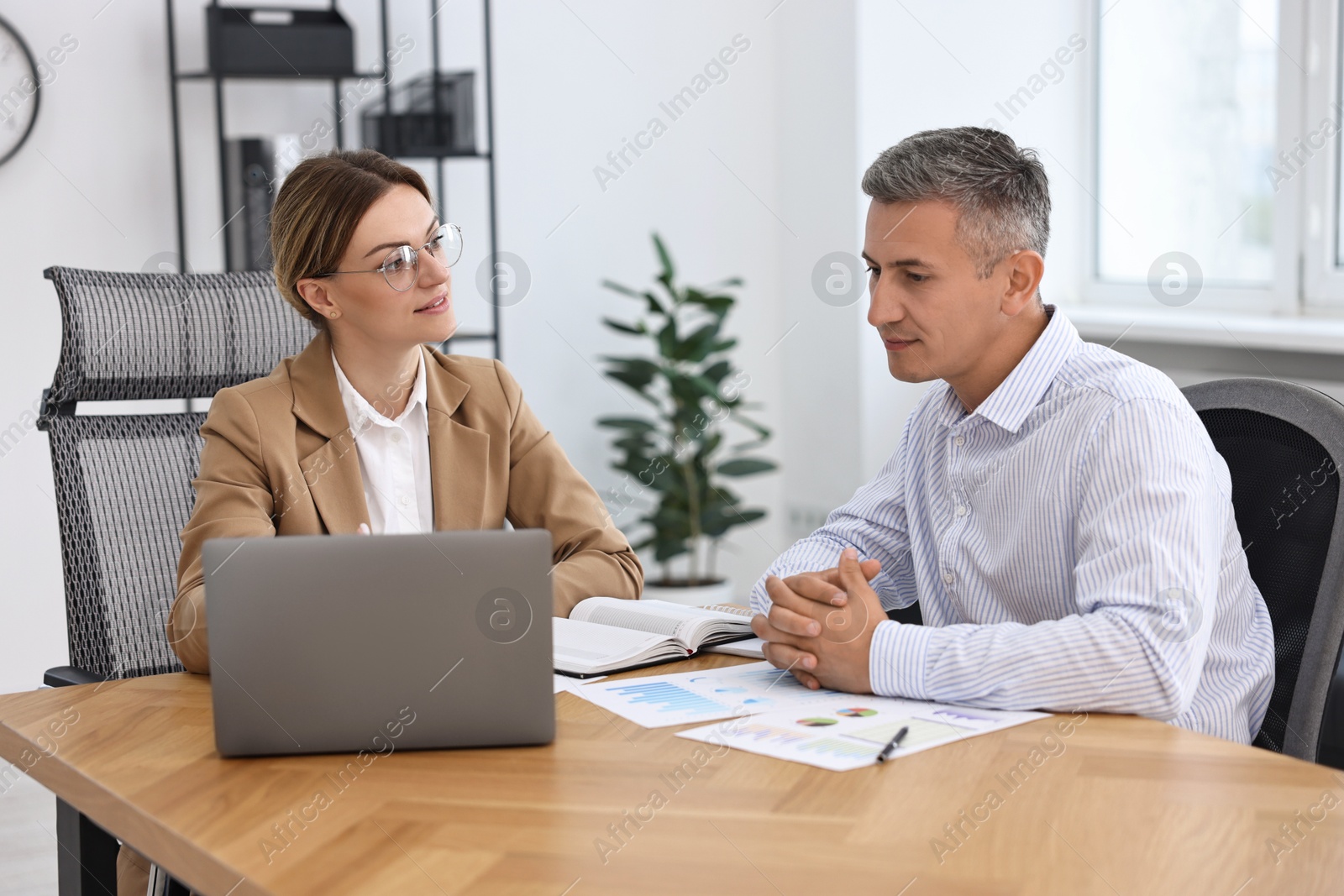 Photo of Banker working with client at wooden table in office