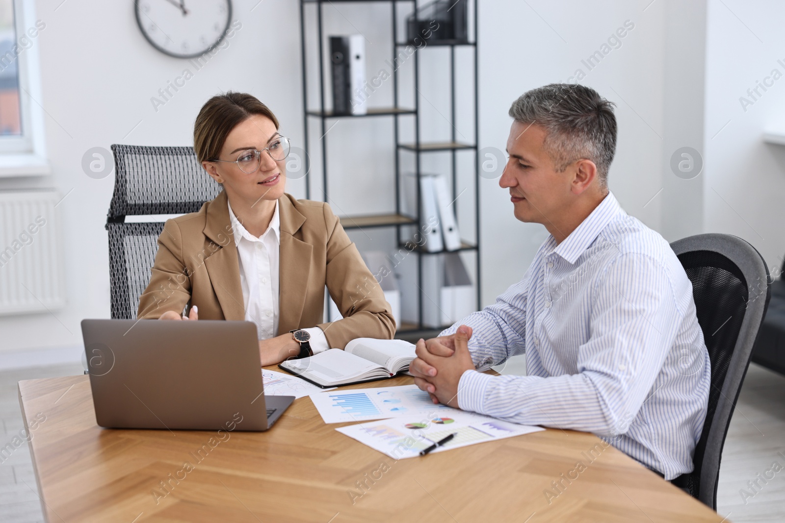 Photo of Banker working with client at wooden table in office