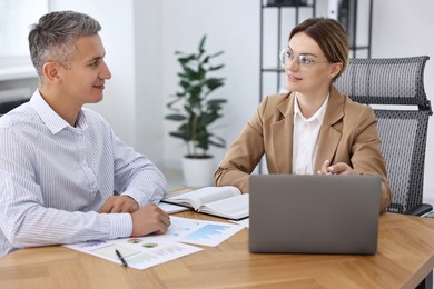 Photo of Banker working with client at wooden table in office