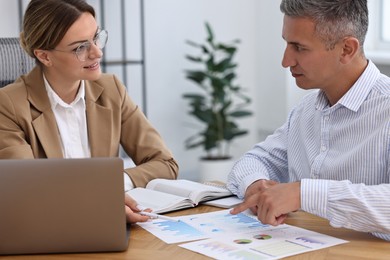 Photo of Banker working with client at wooden table in office