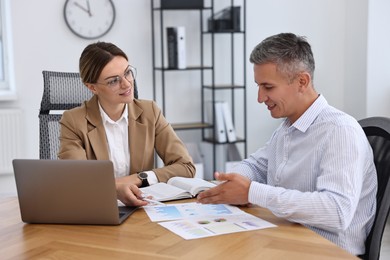 Banker working with client at wooden table in office