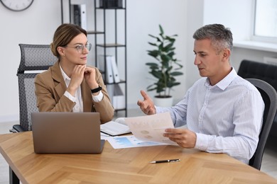 Photo of Banker working with client at wooden table in office