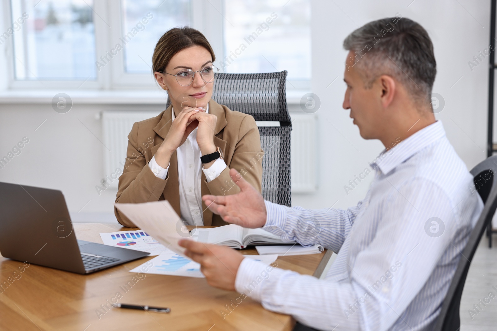 Photo of Banker working with client at wooden table in office