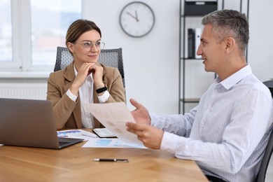 Photo of Banker working with client at wooden table in office