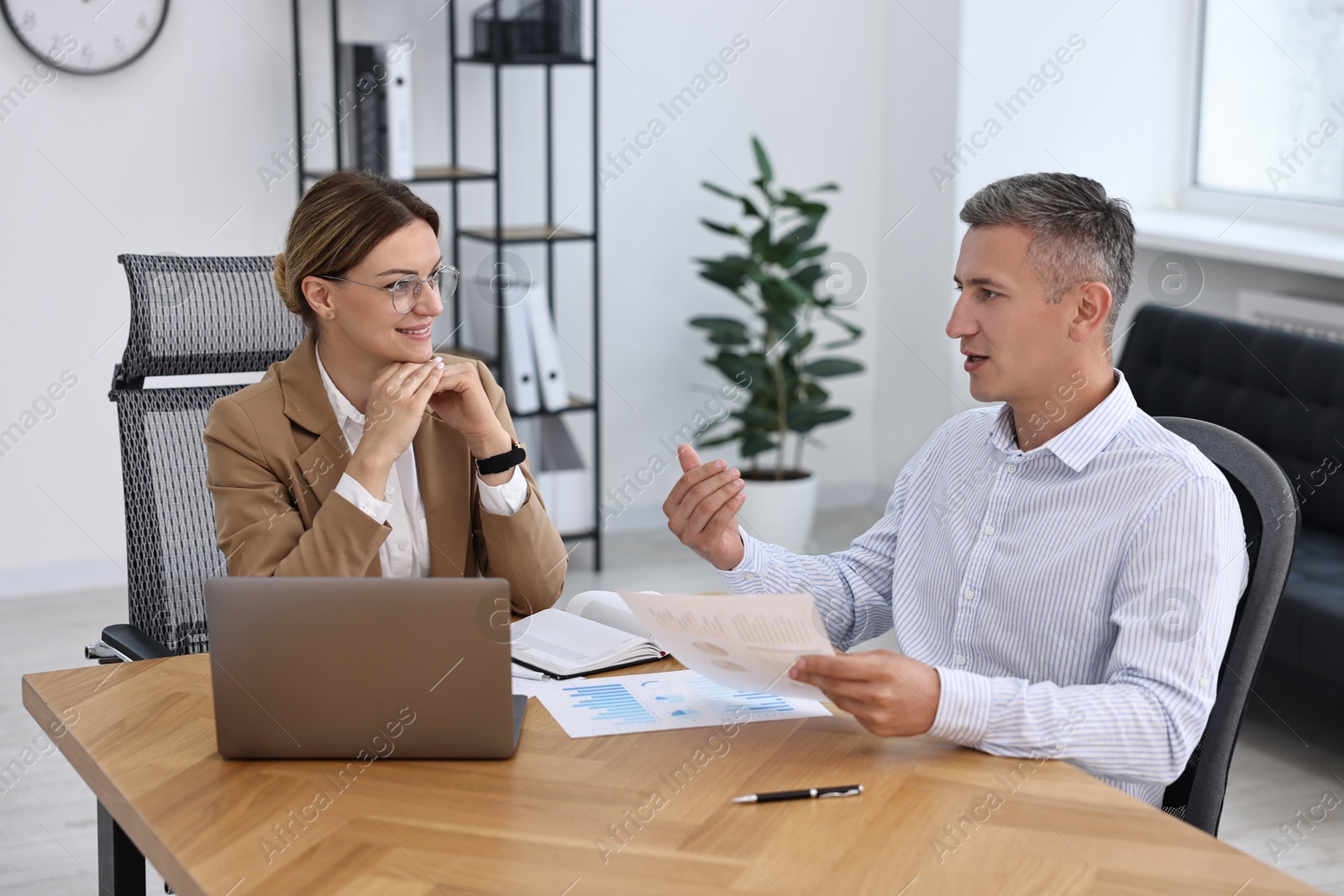 Photo of Banker working with client at wooden table in office