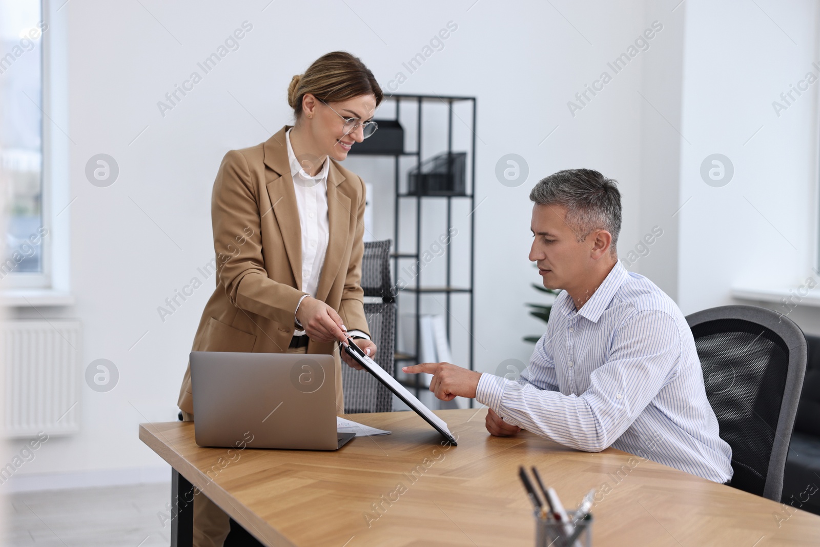 Photo of Banker working with client at table in office