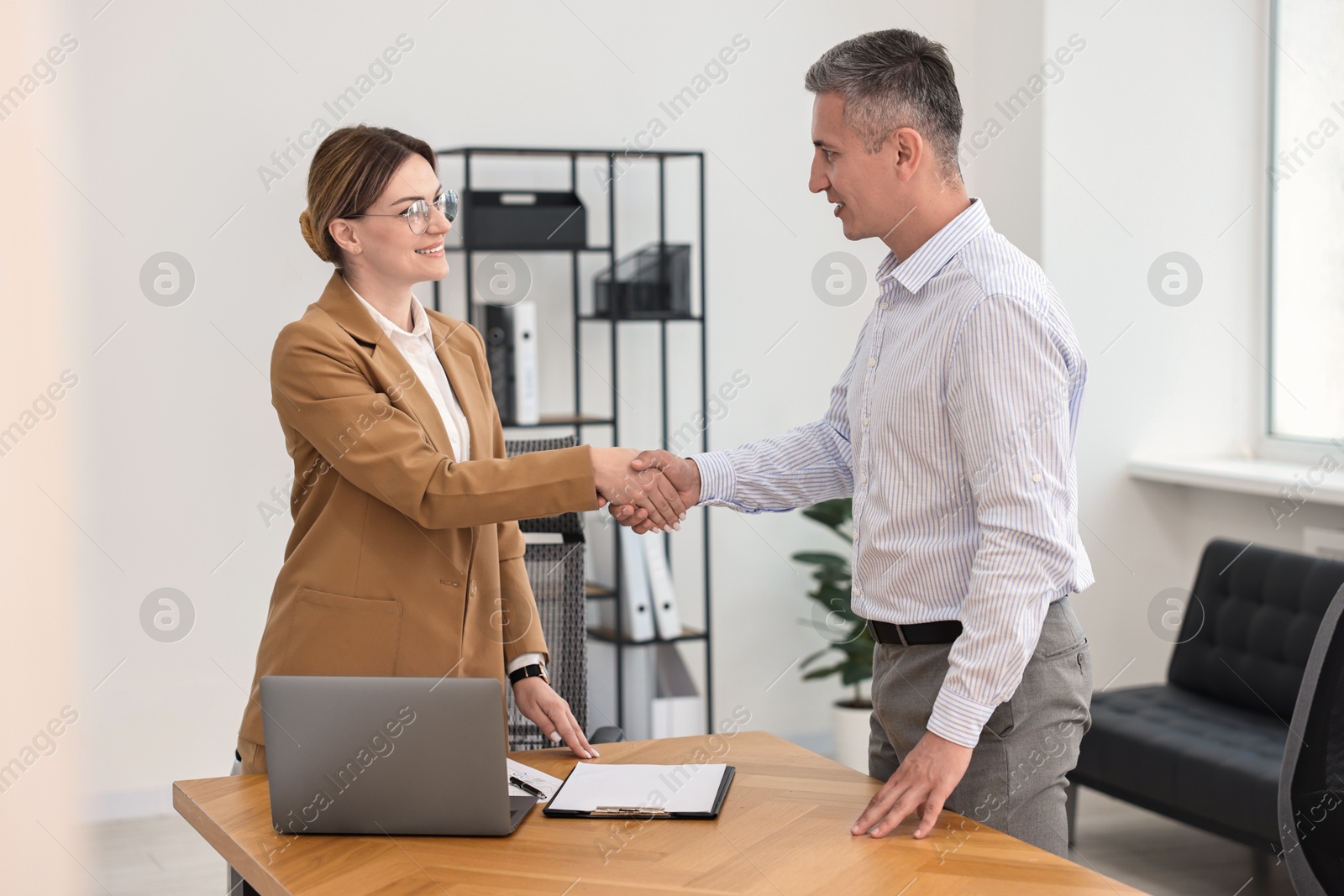 Photo of Banker and client shaking hands in office