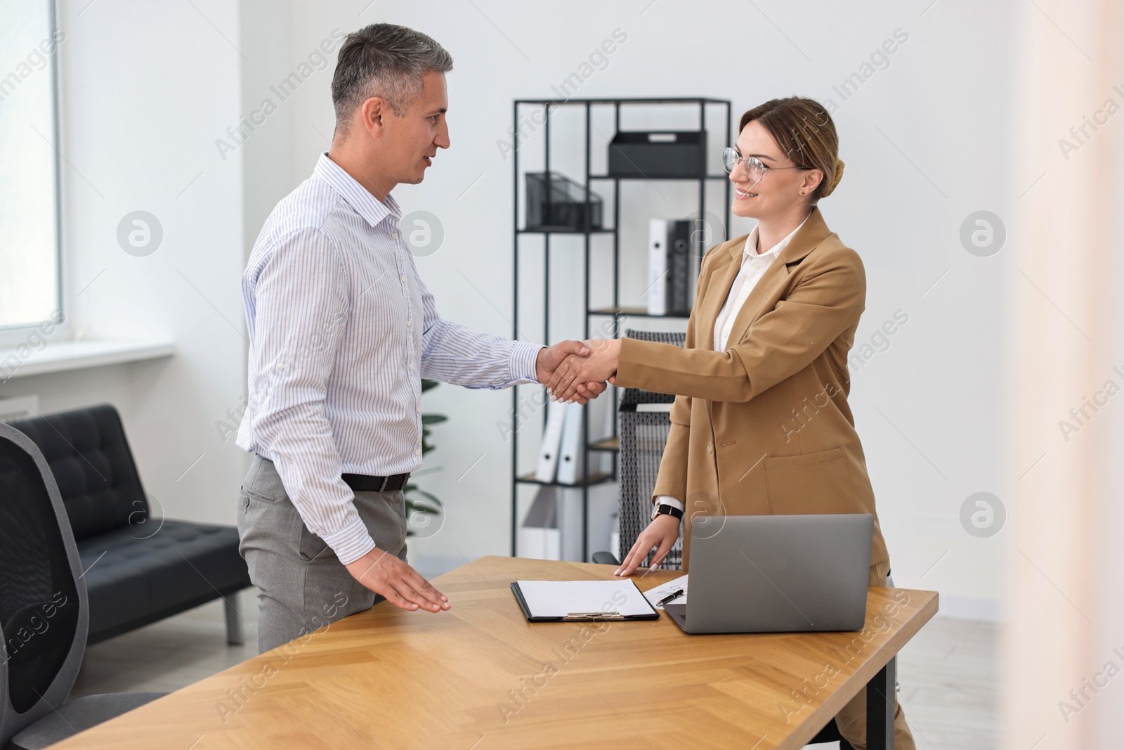 Photo of Banker and client shaking hands in office