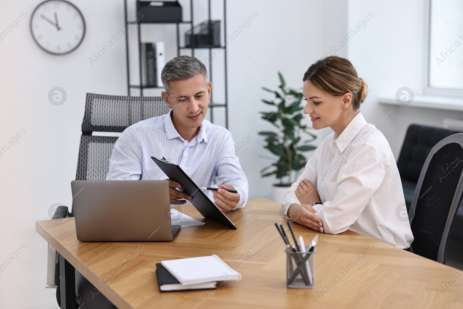 Photo of Banker working with client at wooden table in office