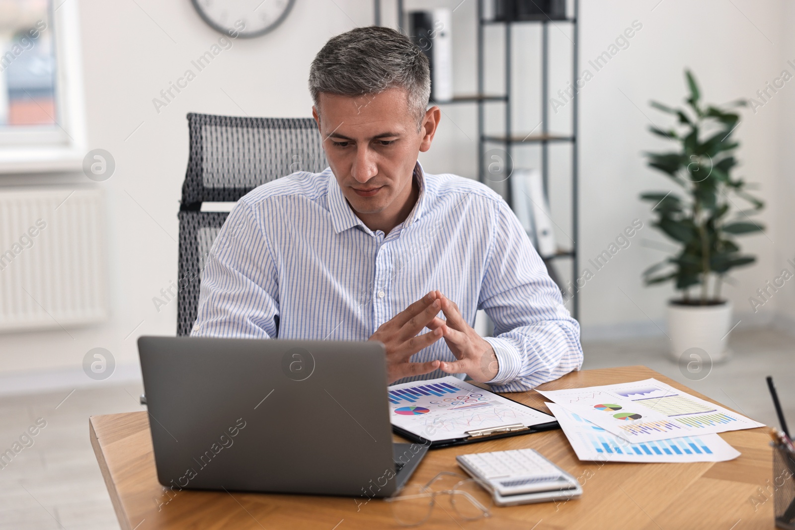 Photo of Banker with laptop working at wooden table in office