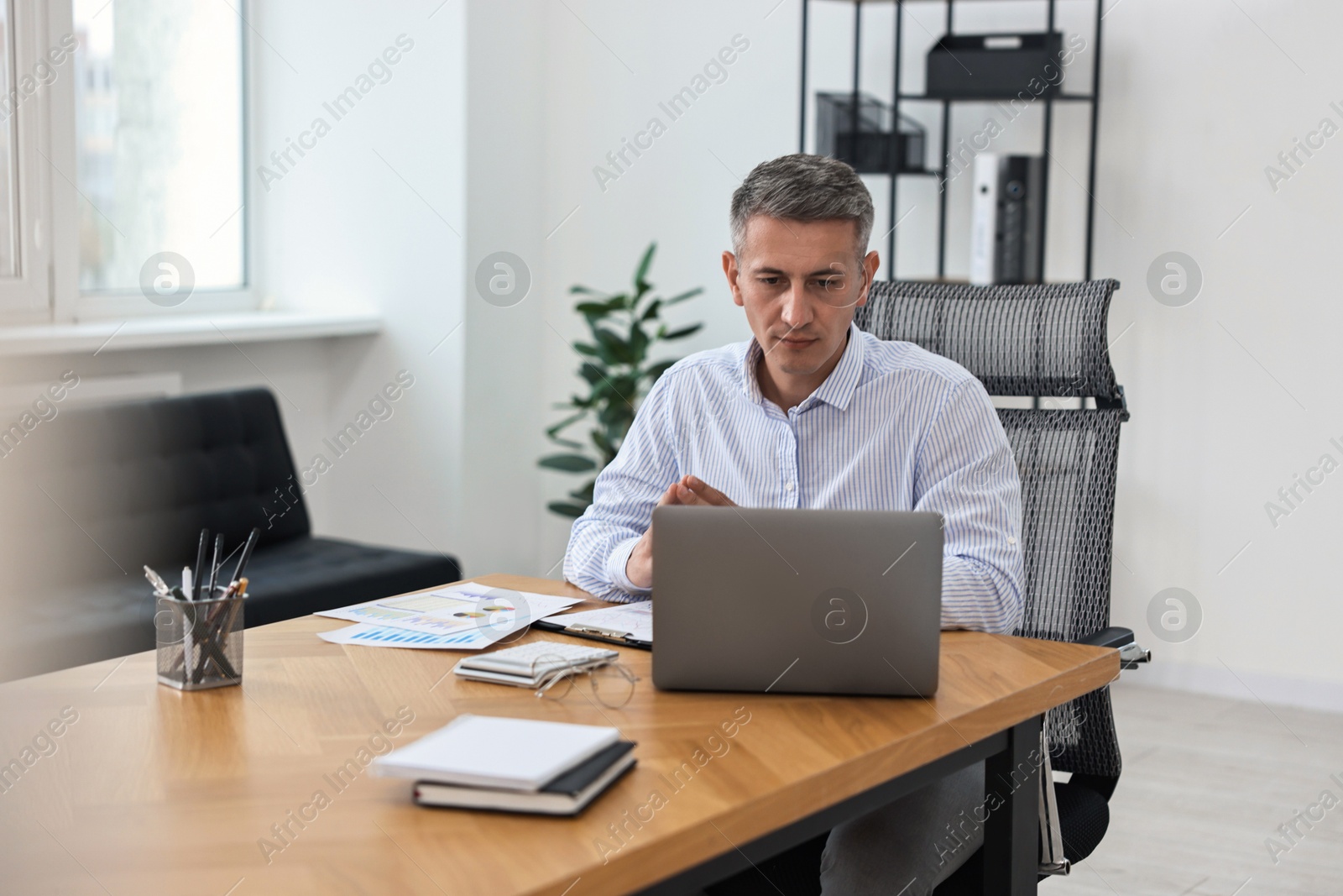 Photo of Banker with laptop working at wooden table in office