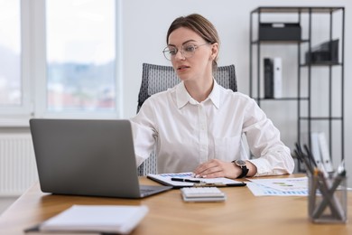 Banker with laptop working at wooden table in office