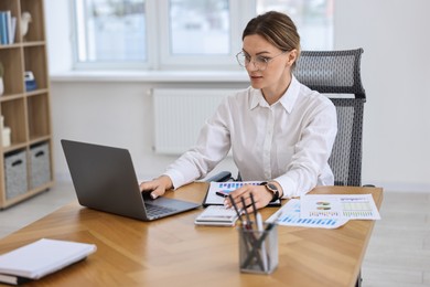 Photo of Banker with laptop and calculator working at wooden table in office