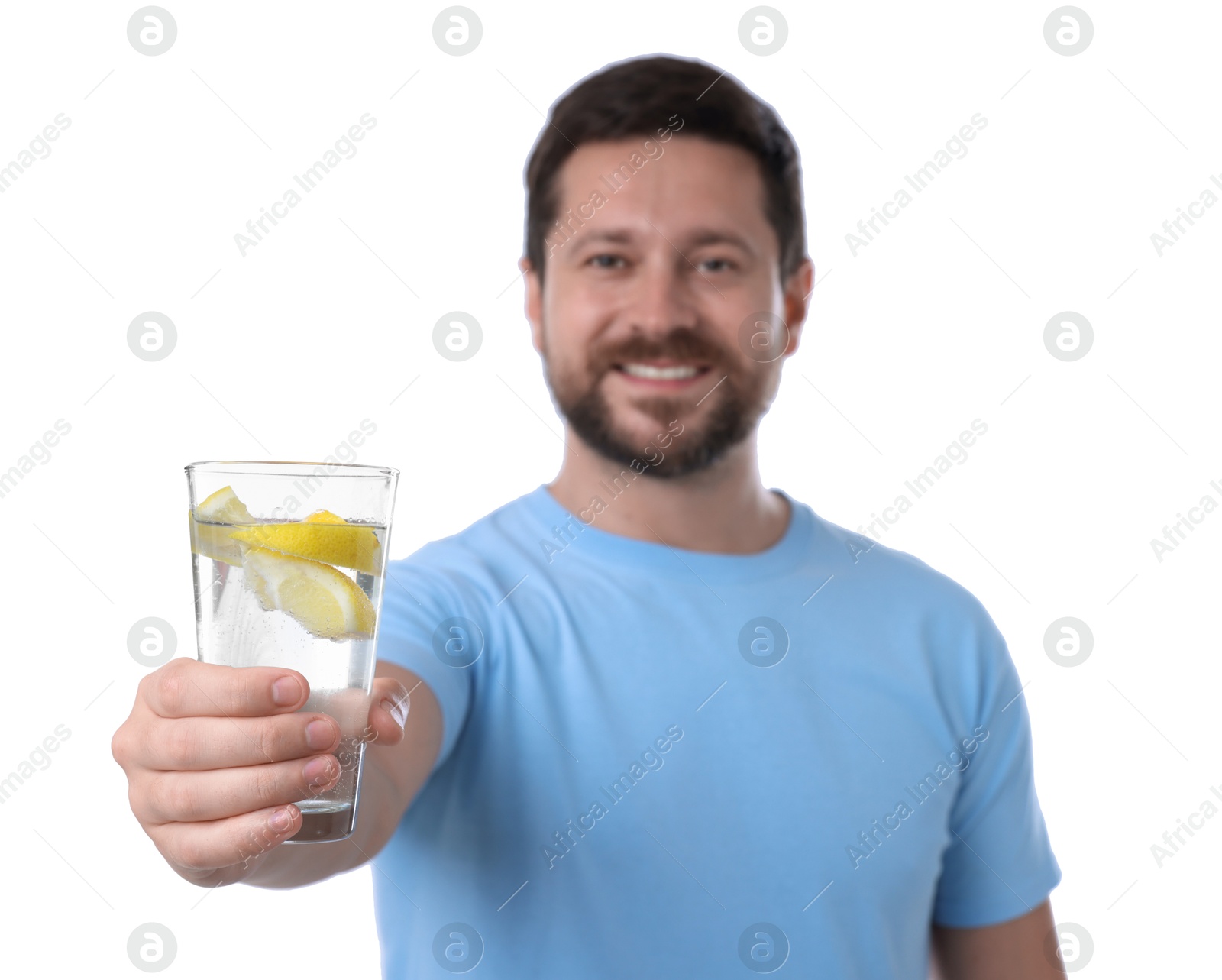 Photo of Happy man showing glass of water with lemon on white background, selective focus