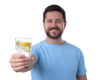 Happy man showing glass of water with lemon on white background, selective focus