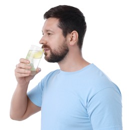 Handsome man drinking water with lemon on white background