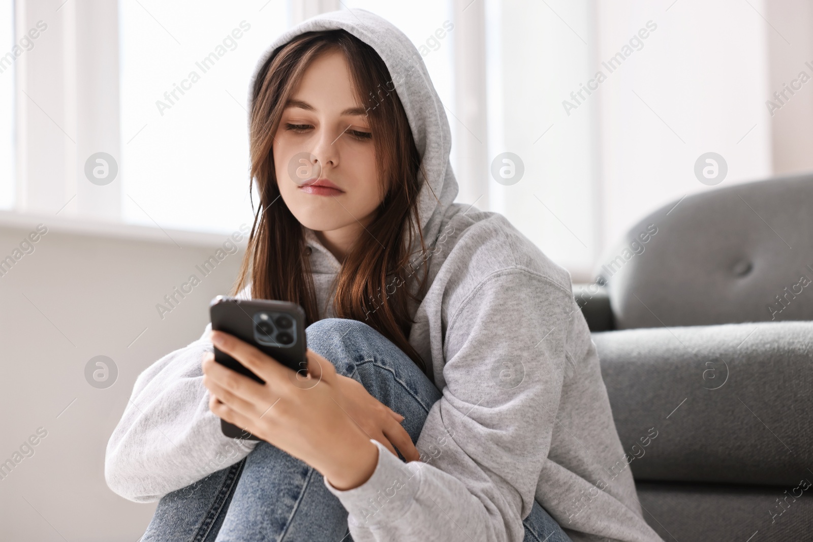 Photo of Loneliness concept. Sad teenage girl using smartphone at home