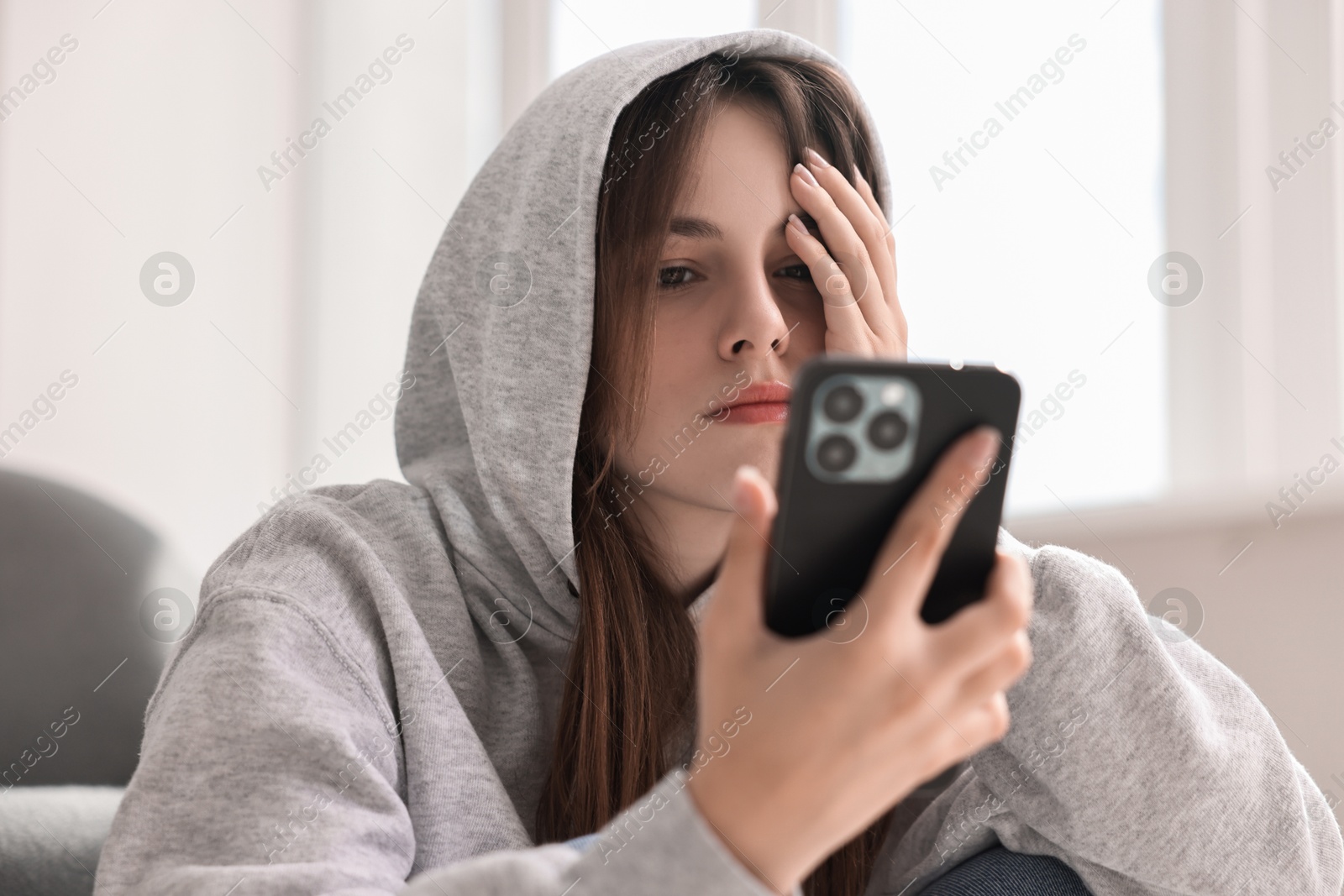 Photo of Loneliness concept. Sad teenage girl using smartphone at home